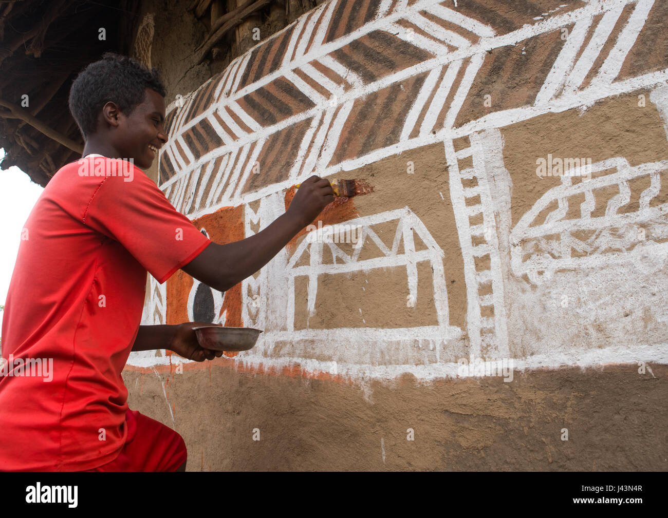 Young man painting the wall of a traditional ethiopian house, Kembata, Alaba Kuito, Ethiopia