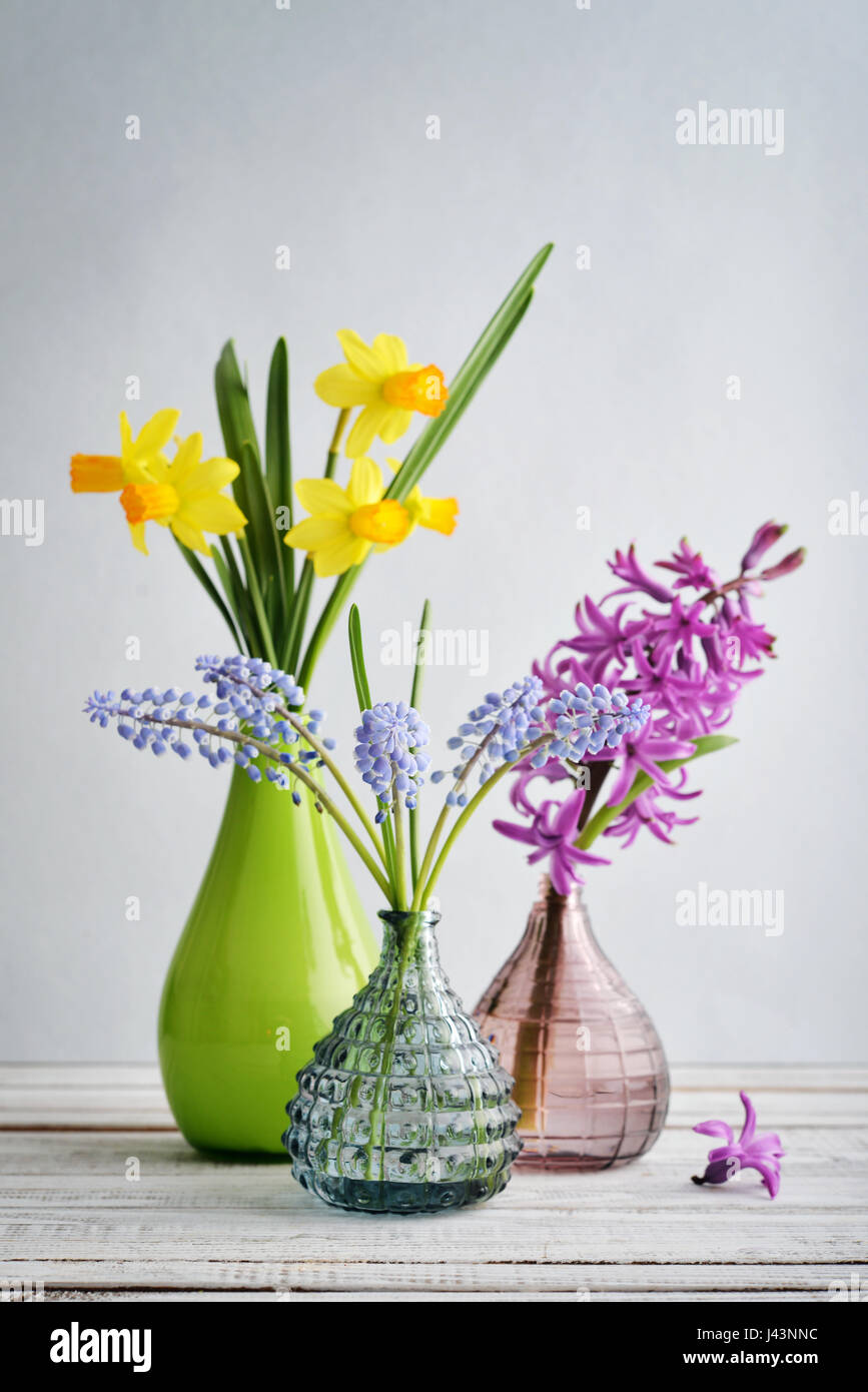 Spring flowers  daffodils, hyacinth and muscari in vases on blue background Stock Photo