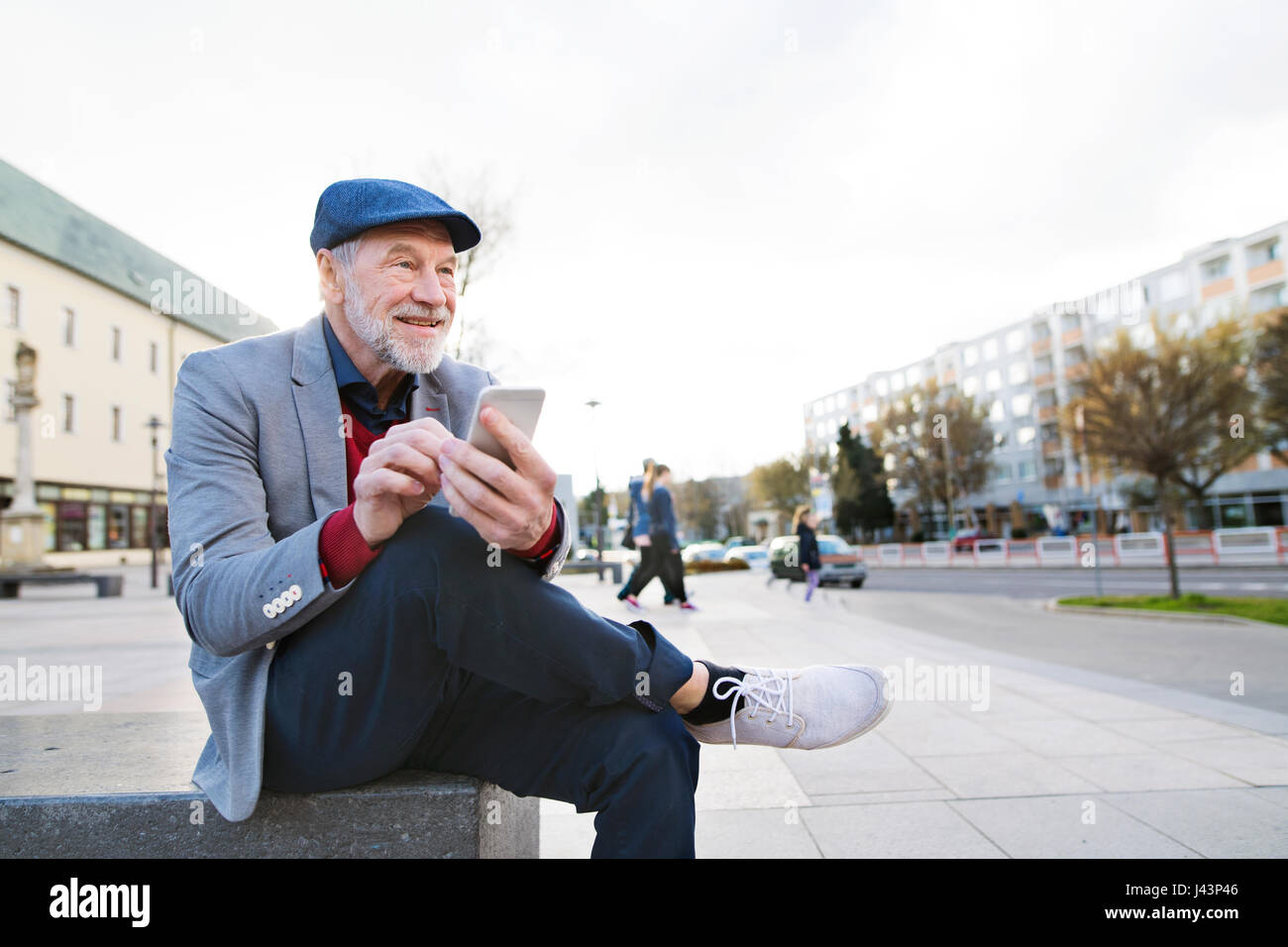 Senior man in town with smart phone, texting Stock Photo