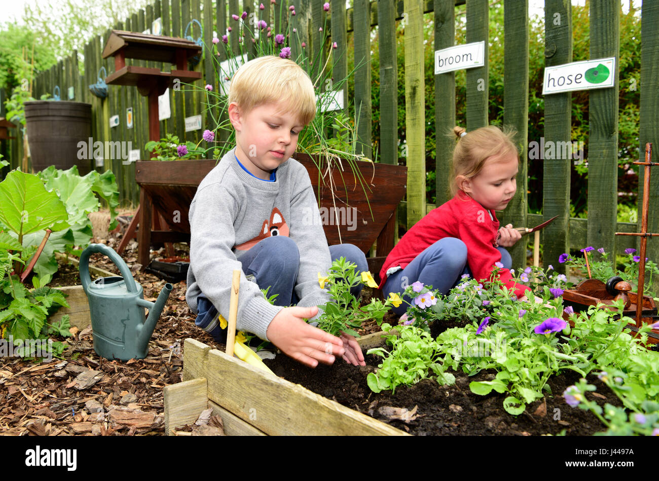 Nursery school kids (both 4 years) gardening, Haslemere, Surrey, UK. Stock Photo