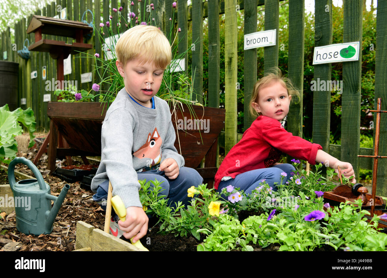 Nursery school kids (both 4 years) gardening, Haslemere, Surrey, UK. Stock Photo