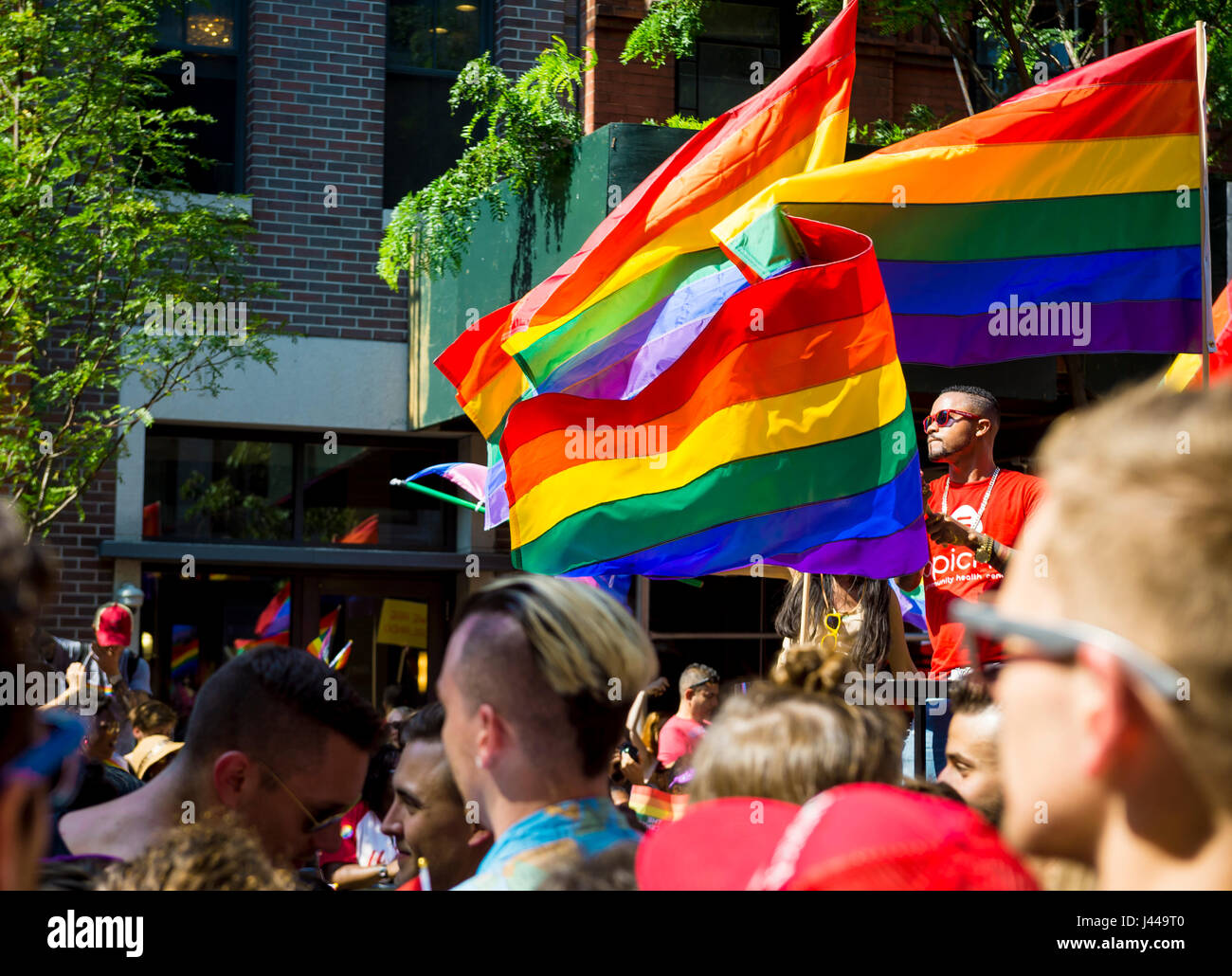 NEW YORK CITY - JUNE 28, 2015: Supporters wave rainbows flags on the sidelines of the annual Pride Parade as it passes through Greenwich Village. Stock Photo