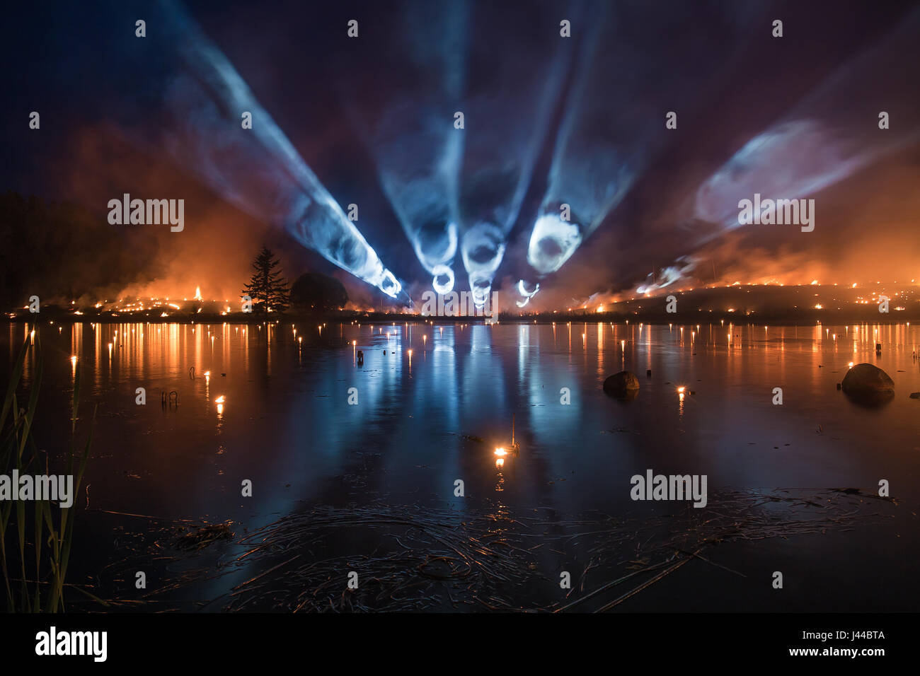 Bright light tubes over a lake with forest fire on background Stock Photo