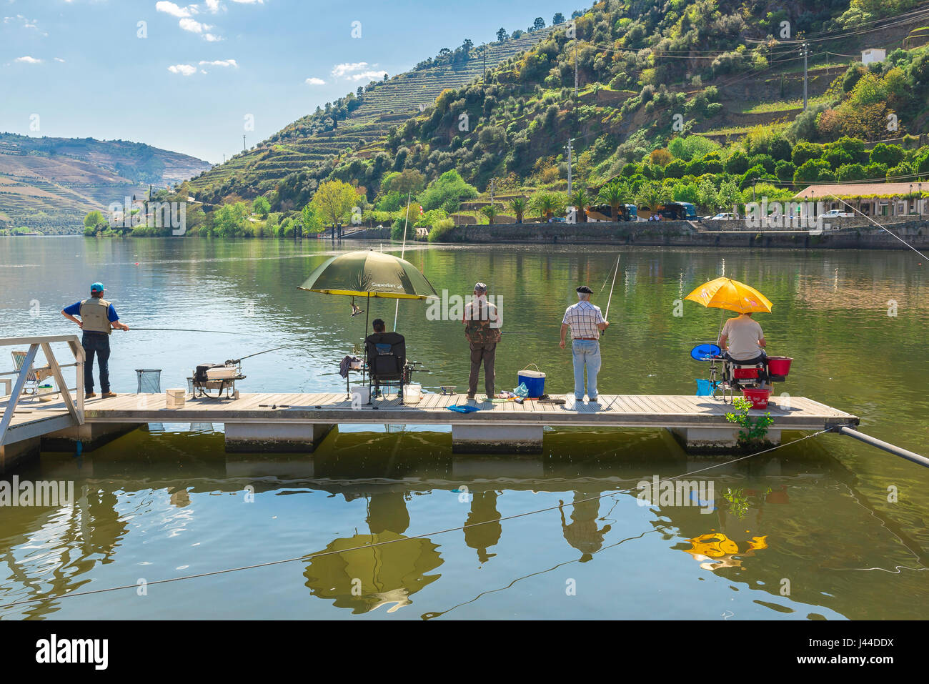 Male friends, view in summer of a group of senior male friends fishing together at a scenic riverside location, Portugal, Europe. Stock Photo