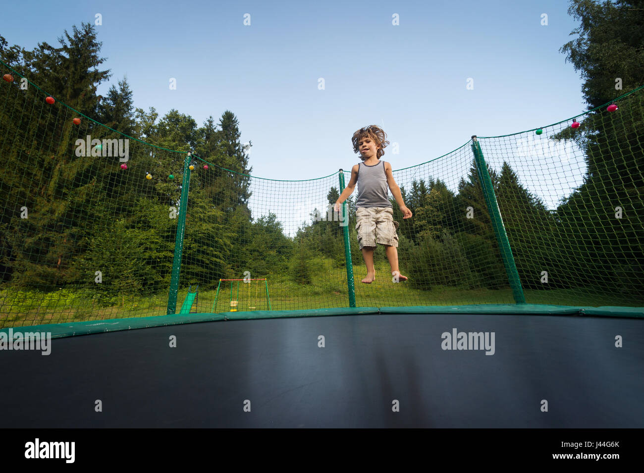 Cute boy enjoys jumping and bouncing on trampoline oudoors Stock Photo ...