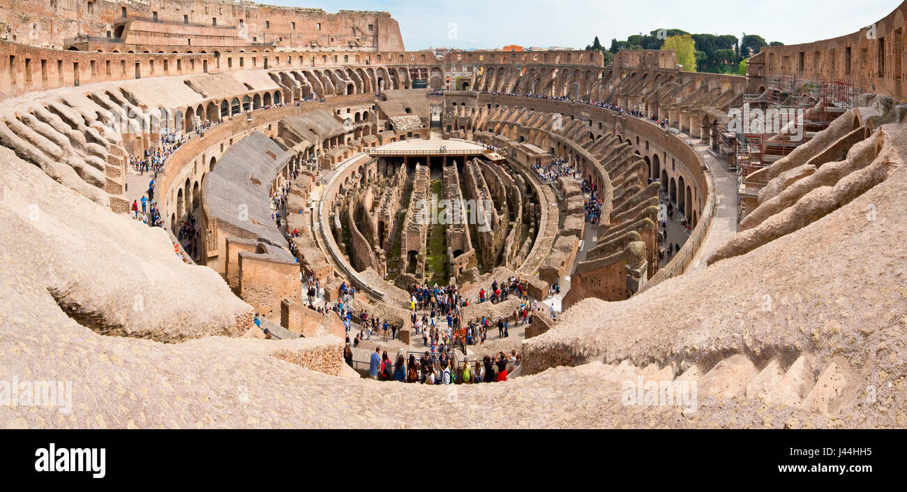 A 2 picture stitch panoramic interior view of the amphitheatre inside the Colosseum with tourists visitors on a sunny day taken from the top level 3. Stock Photo