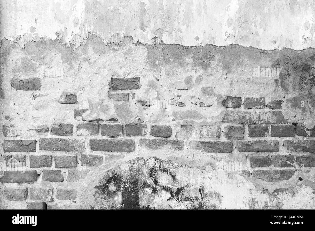 Broken, old and plastered wall revealing old brick wall in black&white. Stock Photo