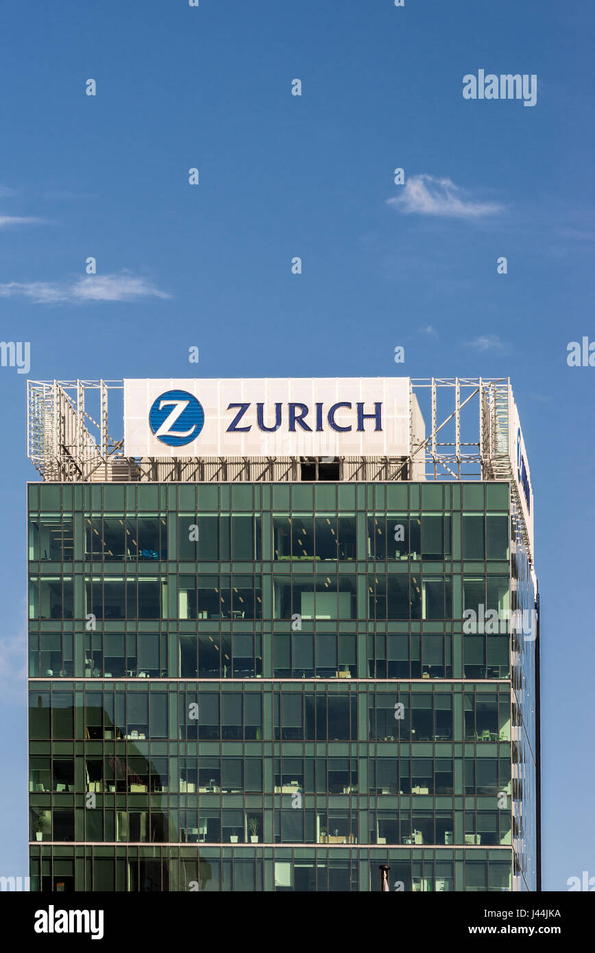 Auckland, New Zealand - March 4, 2017: Green glass office building of Zurich Insurance isolated against blue sky. Large logo and name on top captured  Stock Photo