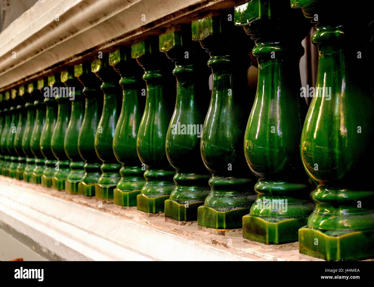 Perspective soft focus view of old stone balustrade with green pillars as vintage background Stock Photo