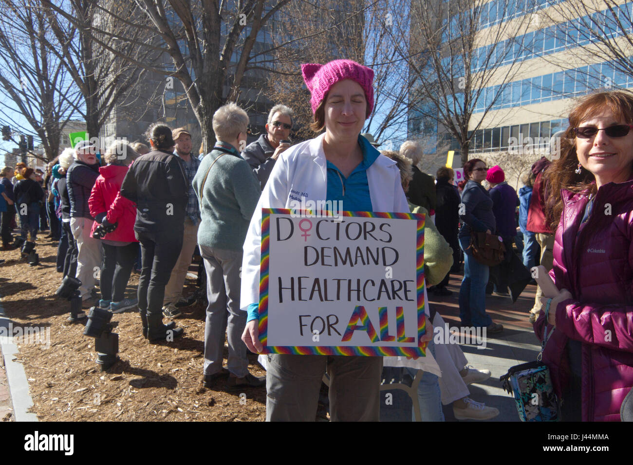 Asheville, North Carolina, USA - February 25, 2017: Woman amid a crowd of protesters wearing a Pussyhat and lab coat holds a colorful sign saying 'Doc Stock Photo