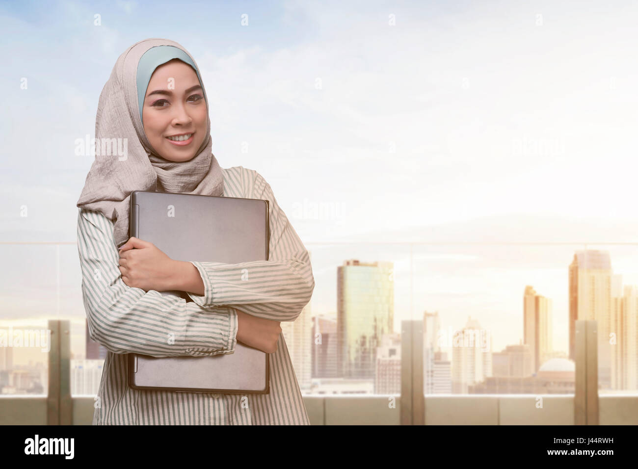 Portrait of asian muslim woman standing with laptop in the office ...
