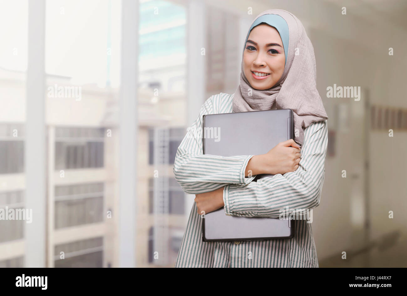 Beautiful asian muslim woman holding laptop in the office Stock Photo ...