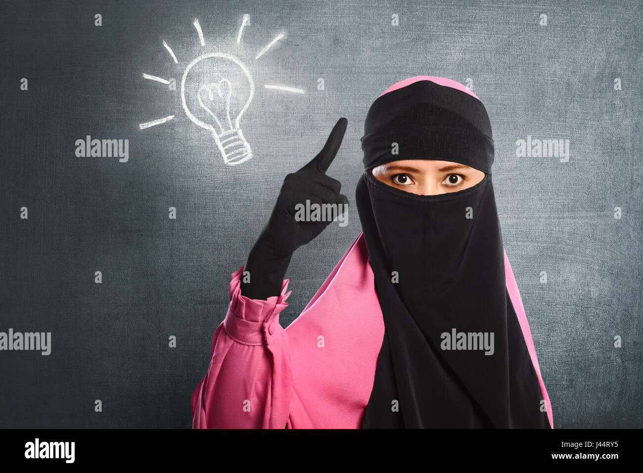 Young asian muslim woman wearing hijab having new idea with blackboard background Stock Photo