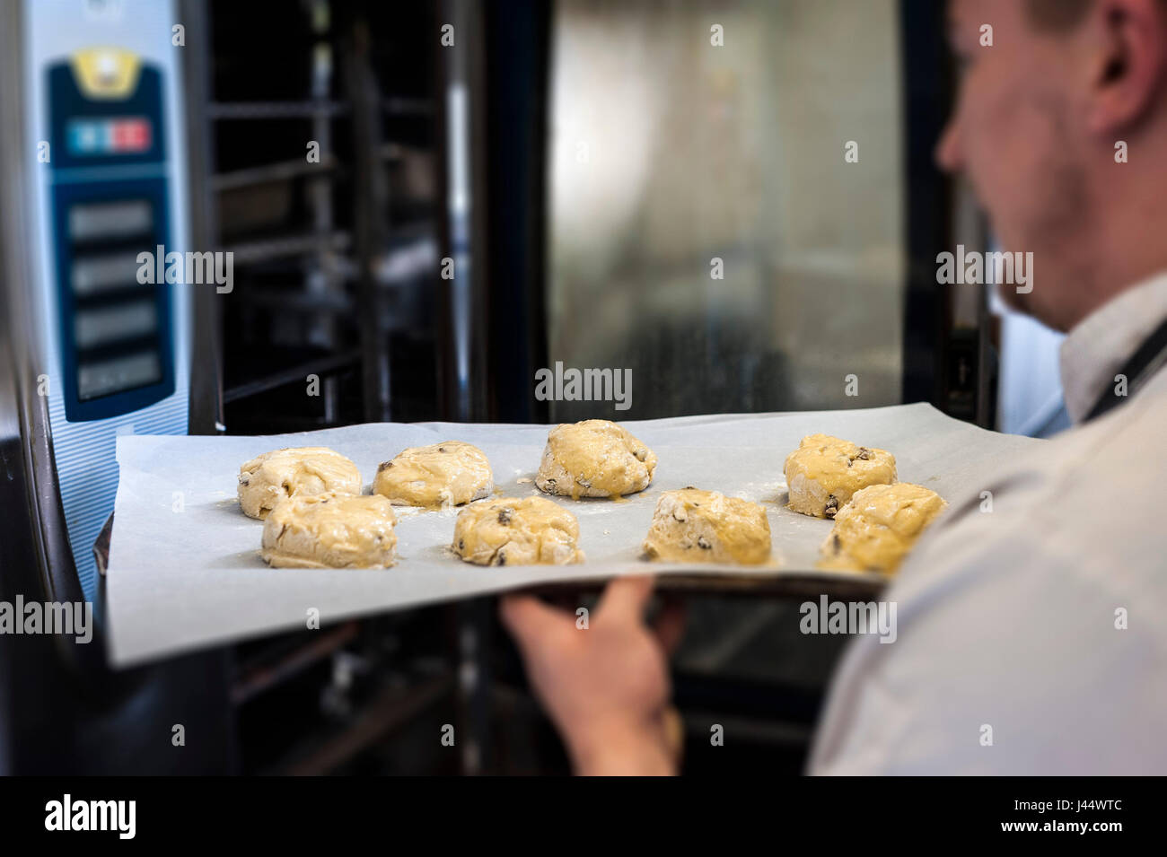 A chef puts a tray of scones into an oven Kitchen Food Cooking Baking Restaurant Food preparation Food service industry Worker Working Stock Photo