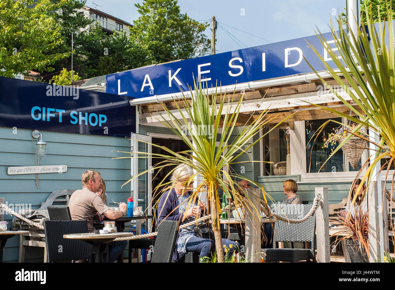 Customers sitting in an outside area of a cafe People Taking a break Relaxing sunshine Sunny Al fresco dining Sign Signs Lakeside restaurant Stock Photo
