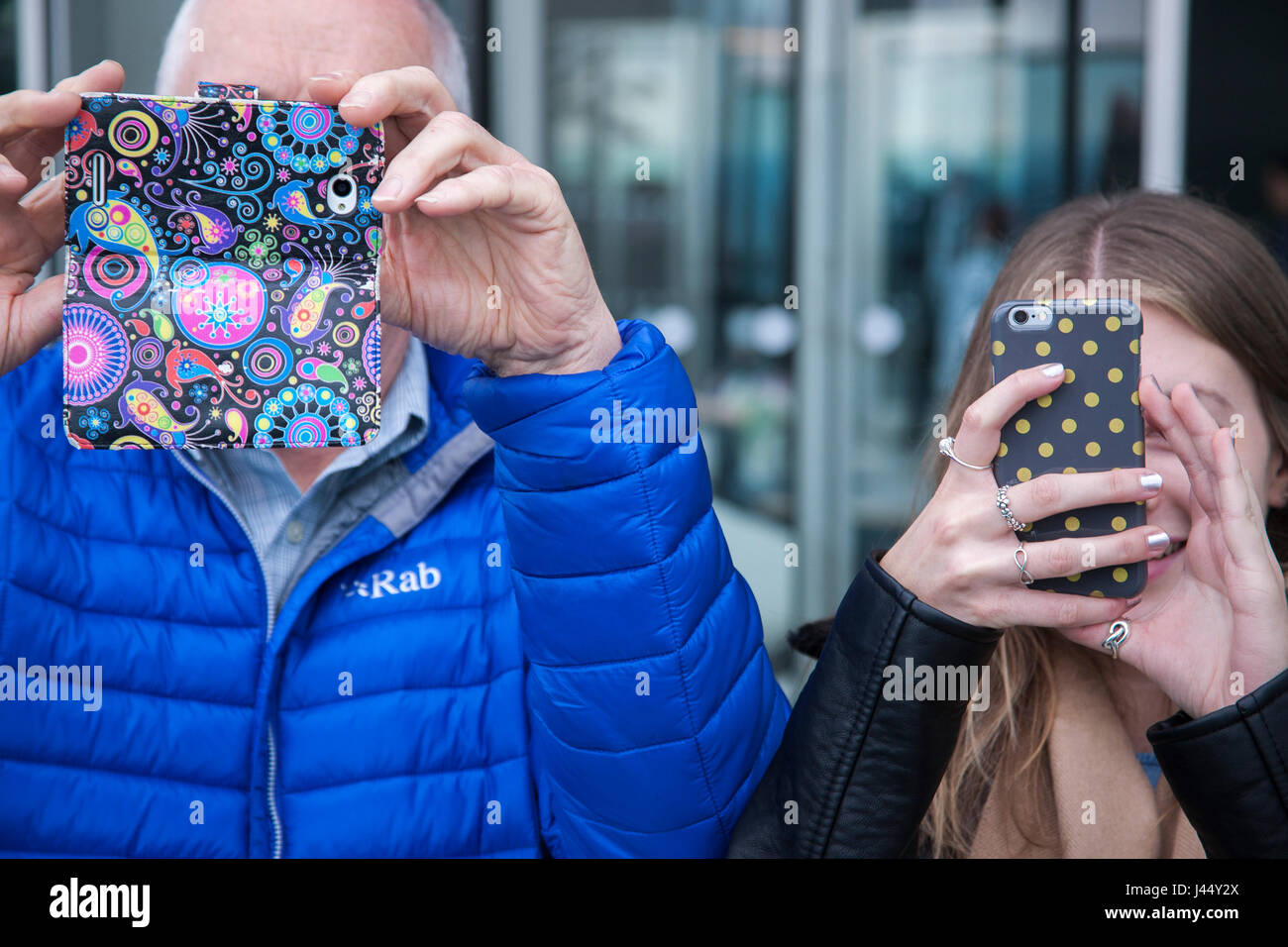 camera phones held up covering faces as man and woman take photographs Stock Photo