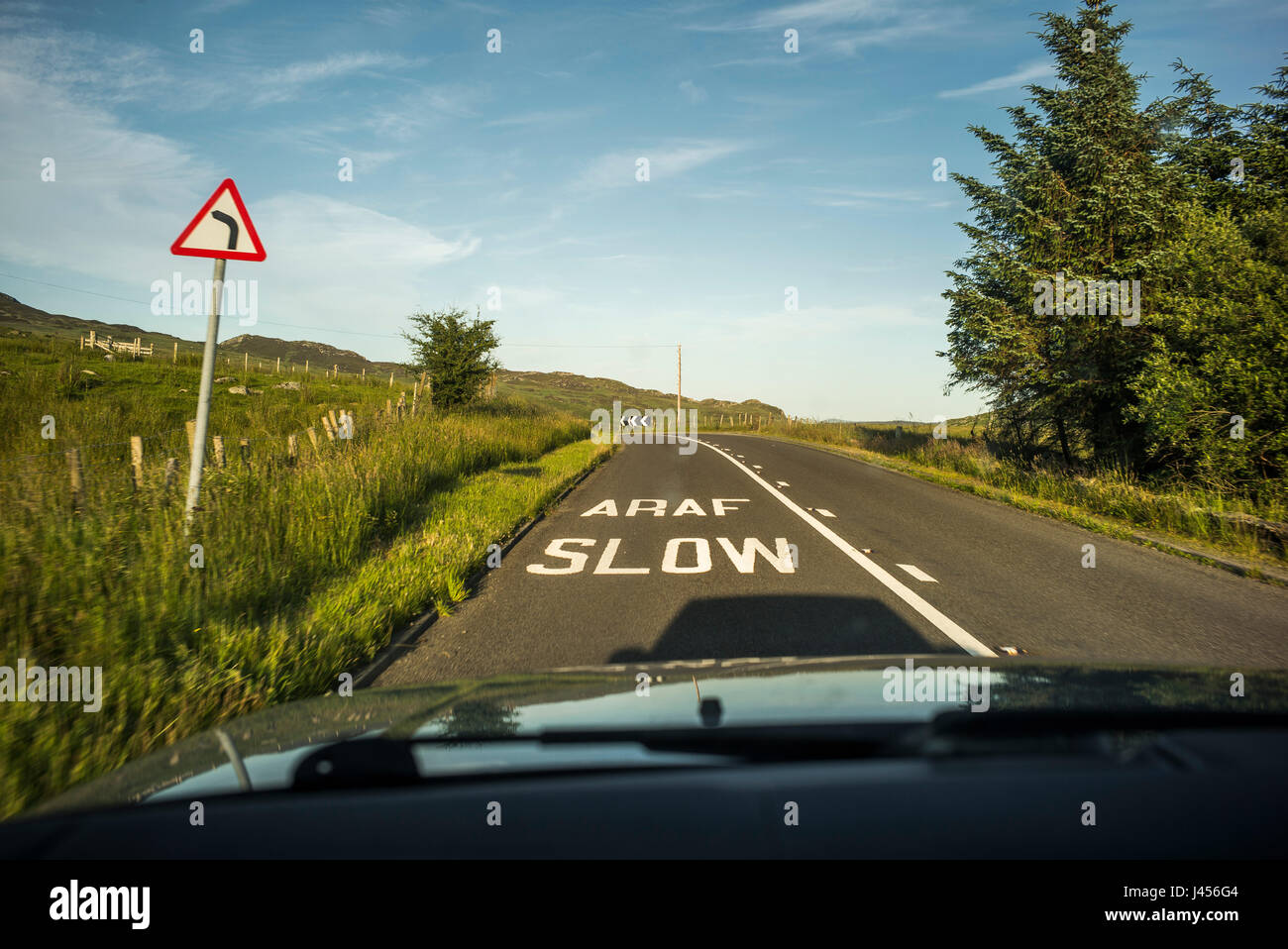 A slow sign in English and Welsh seen from inside a car painted on the tarmac before a bend in the road in Snowdonia, Wales,U.K. Stock Photo