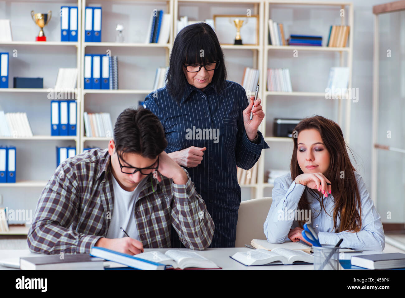 Young student and teacher during tutoring lesson Stock Photo - Alamy
