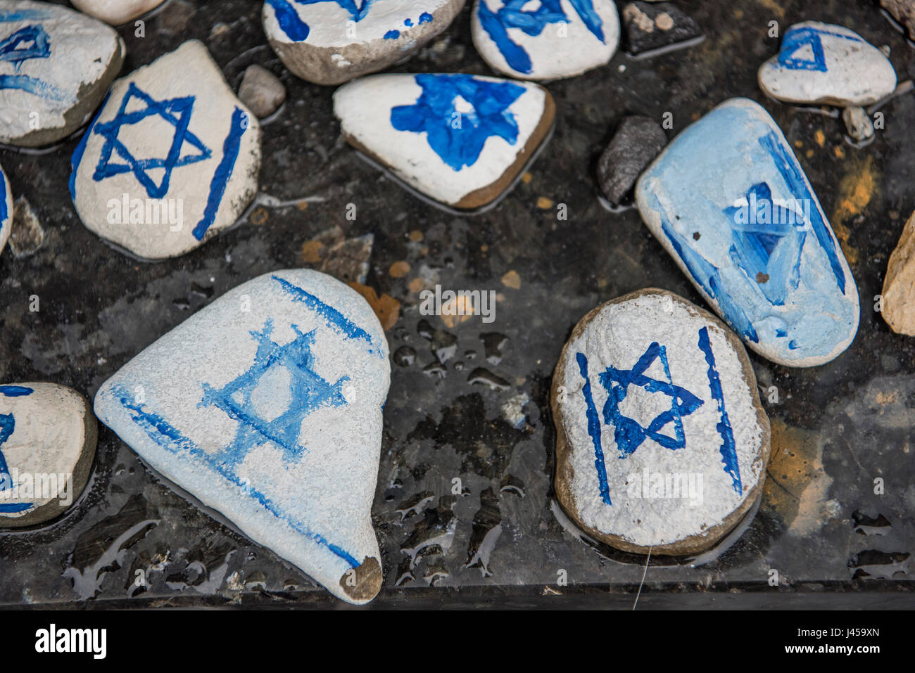 Hand painted stones with the Star of David painted on them left by visitors at the base of the Warsaw Ghetto Heroes Monument. Stock Photo