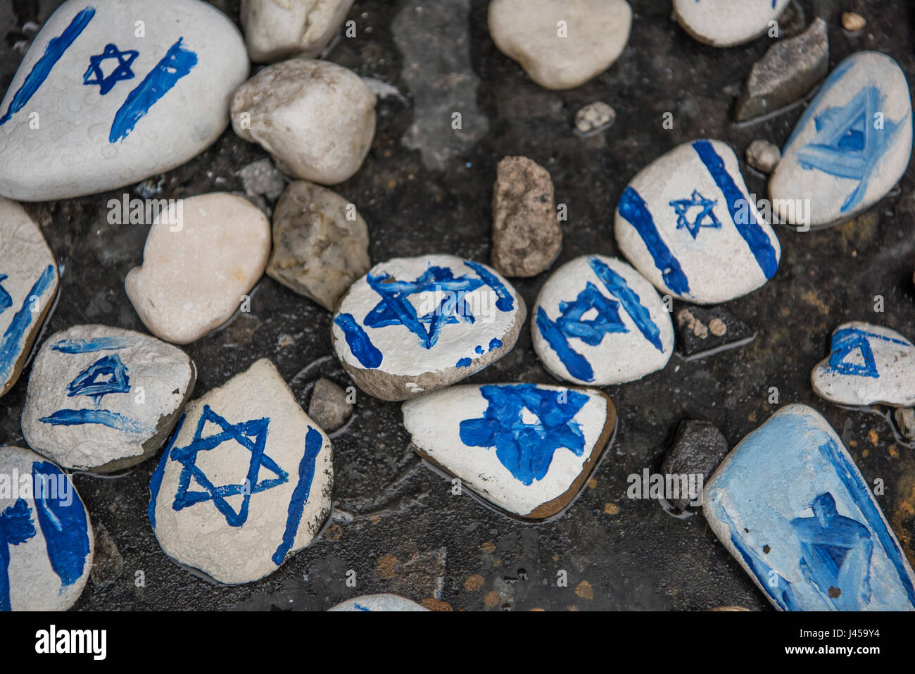 Hand painted stones with the Star of David painted on them left by visitors at the base of the Warsaw Ghetto Heroes Monument. Stock Photo