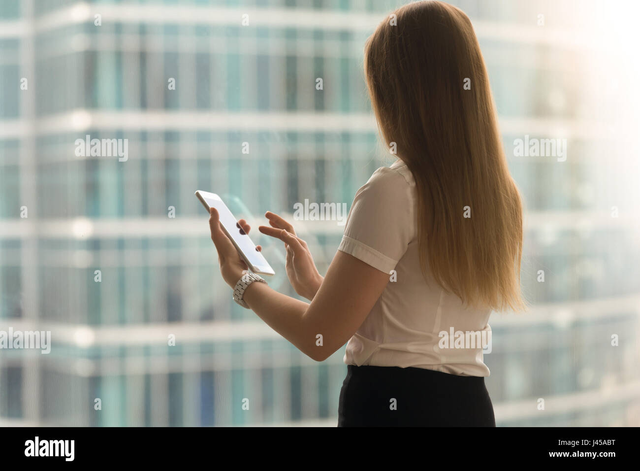 Woman back view swipe with finger on tablet screen Stock Photo