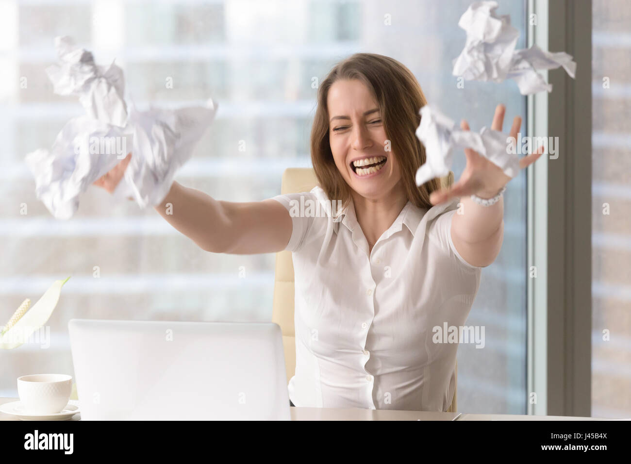 Angry businesswoman throwing crumbled papers Stock Photo