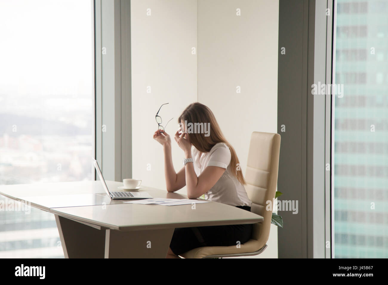 Exhausted businesswoman sitting at office Stock Photo
