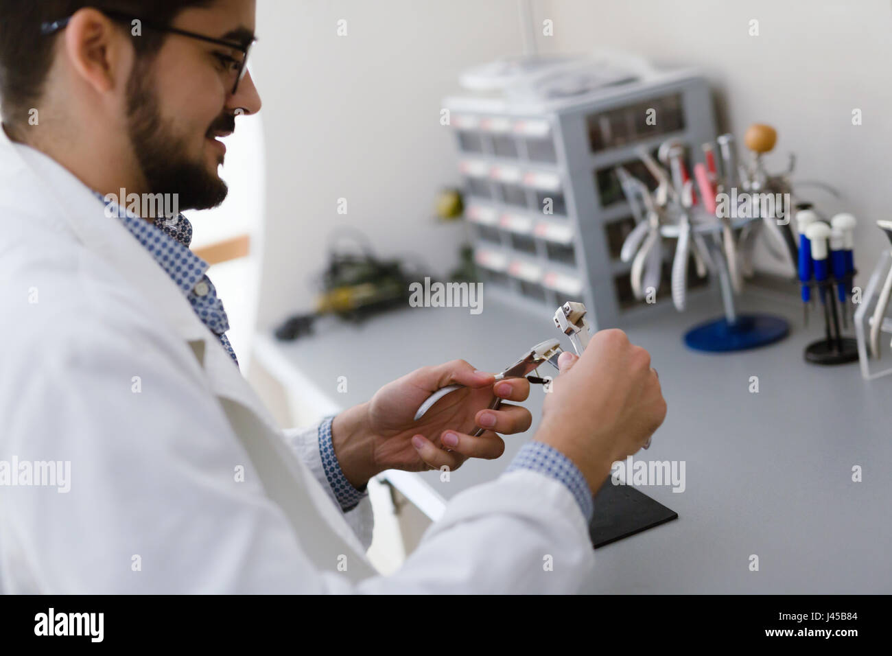 Optician repairing and fixing eye glasses at optical store Stock Photo