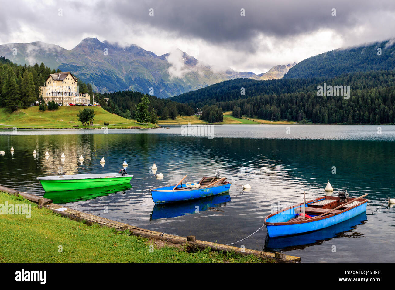Blue and green boats on the mountain lake of St. Moritz on a cloudy day in the summer (Sankt Moritz, Engadin, Grisons, Switzerland) Stock Photo