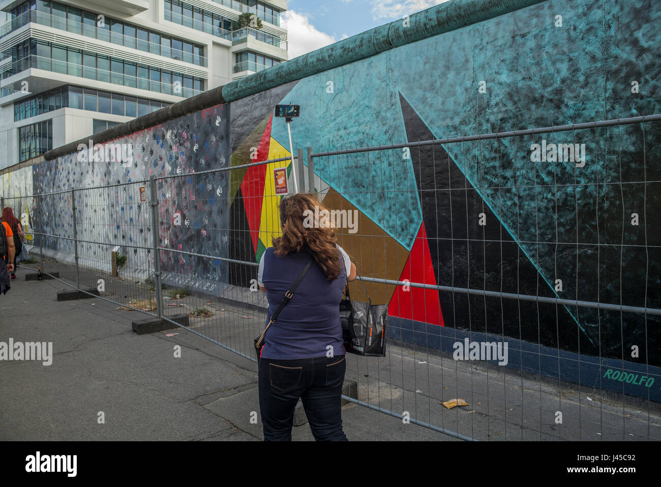 Tourists take pictures of a section of the East Side Gallery on Mühlenstrasse, Berlin, site of the few last remaining parts of the Berlin Wall adorned Stock Photo