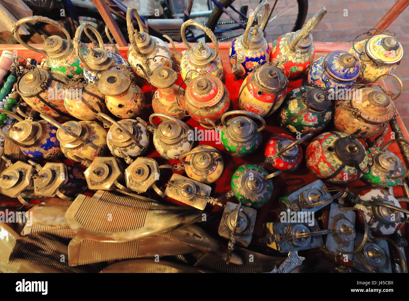 Vitreous enamel old teapots -some of them spout and handle missing- along with bone and antler combs displayed on sale as souvenirs. Showcase of a str Stock Photo