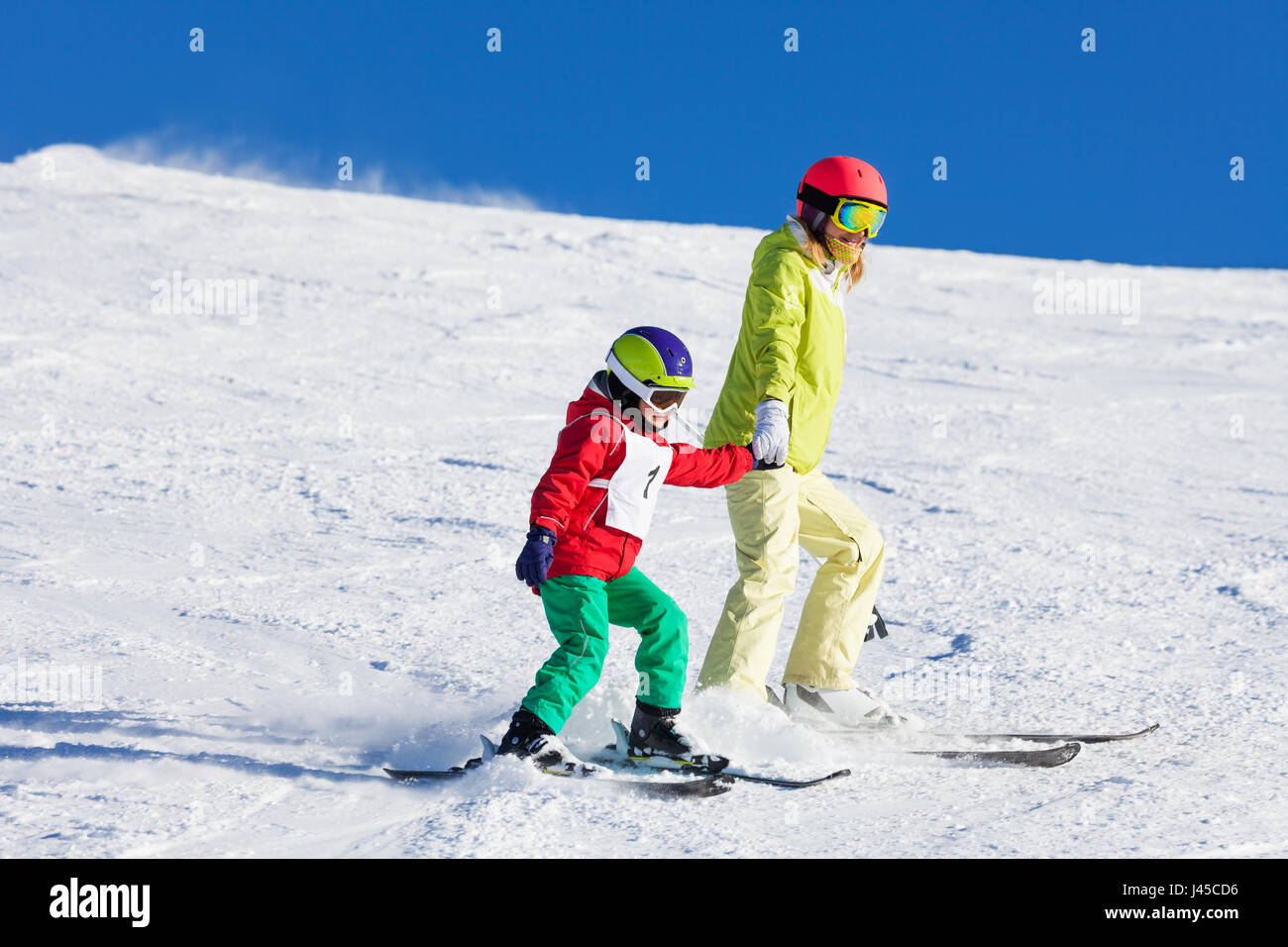 Active mother teaching son skiing holding hands Stock Photo