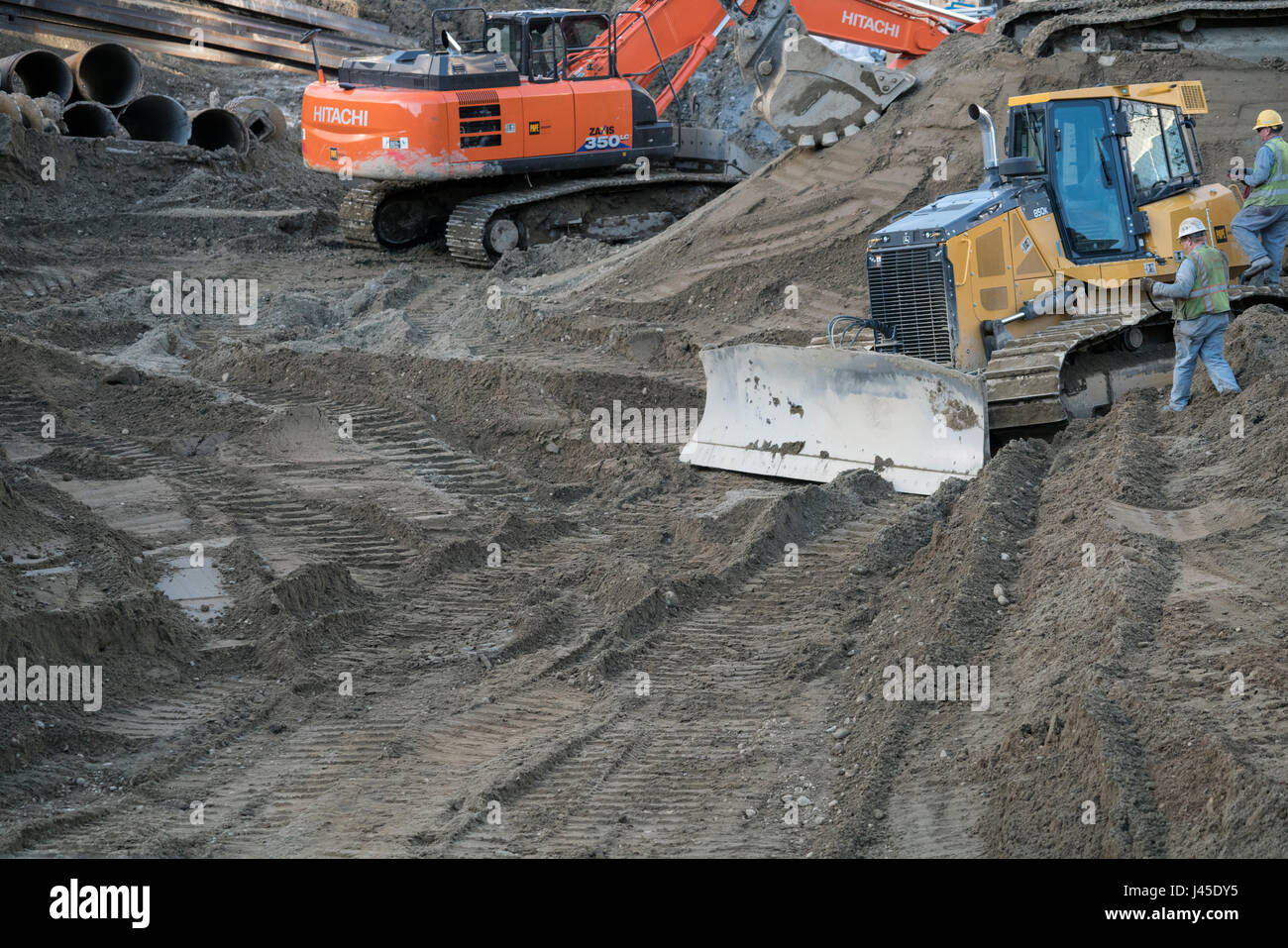 Earth moving machines on site digging a hole in the ground for a building. Stock Photo