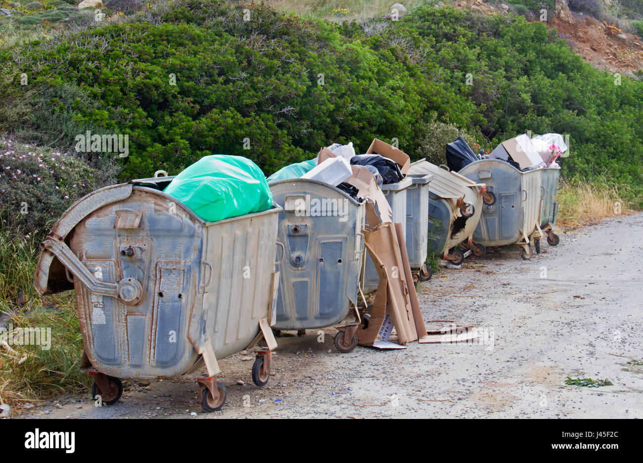 Four overloaded wheeled trashbins Stock Photo