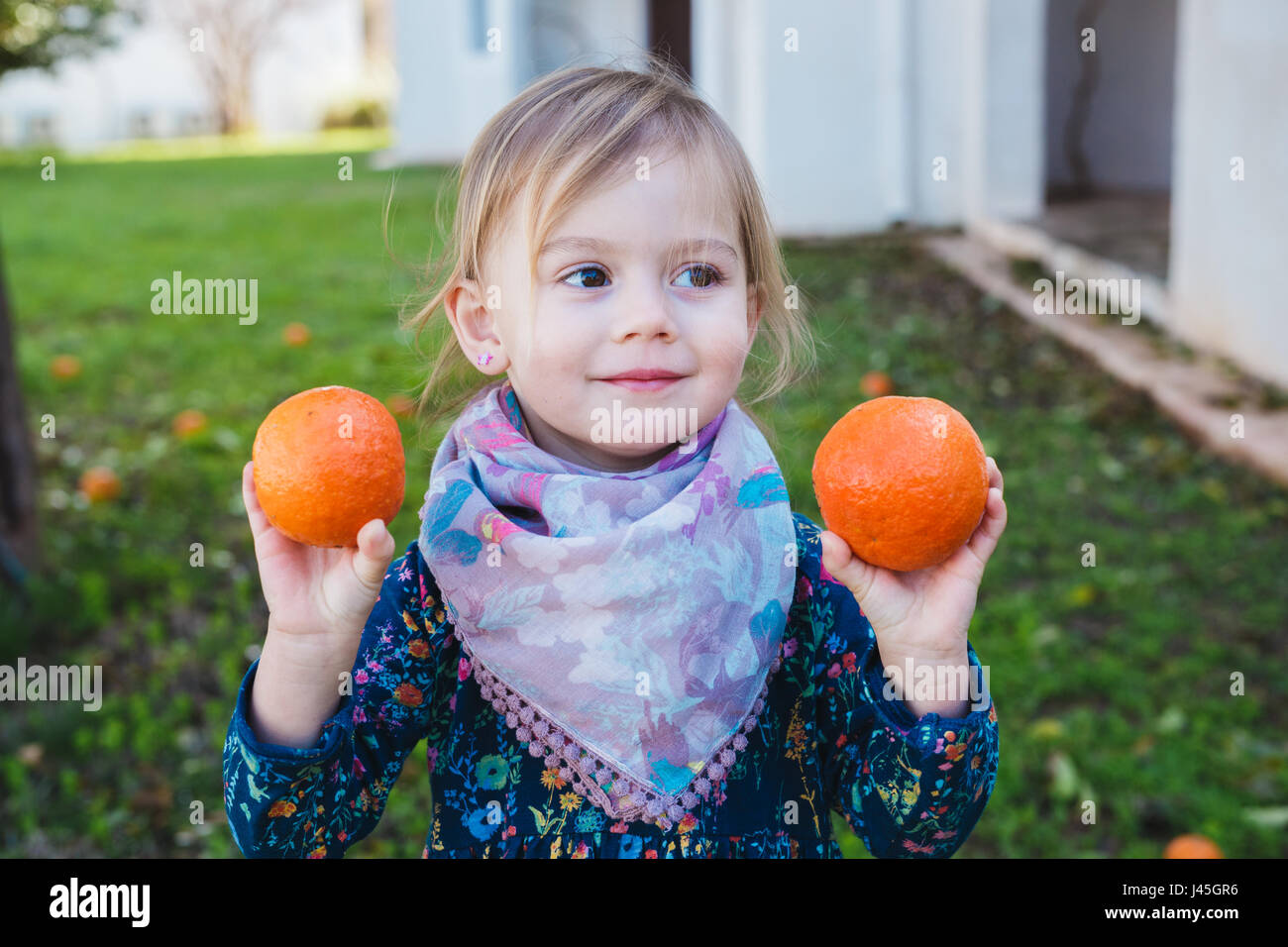 Little girl holding oranges in the garden Stock Photo - Alamy
