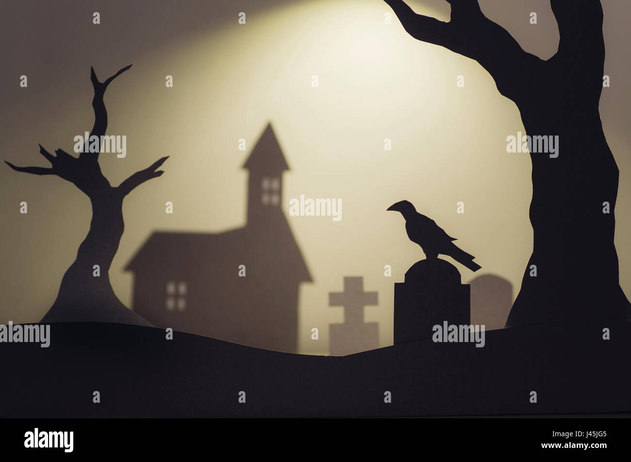 Halloween paper cutout landscape. Graveyard with crow on tombstone, old trees and haunted house Stock Photo