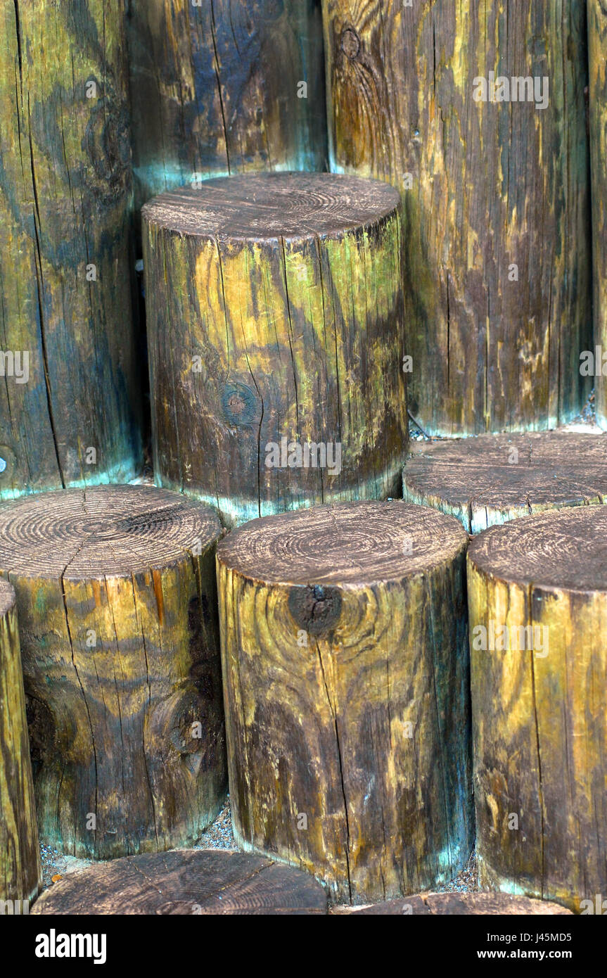 Round wooden timbers are staggered in heights to form unusual steps.  Wood is weathered and stained with yellow and blue. Stock Photo