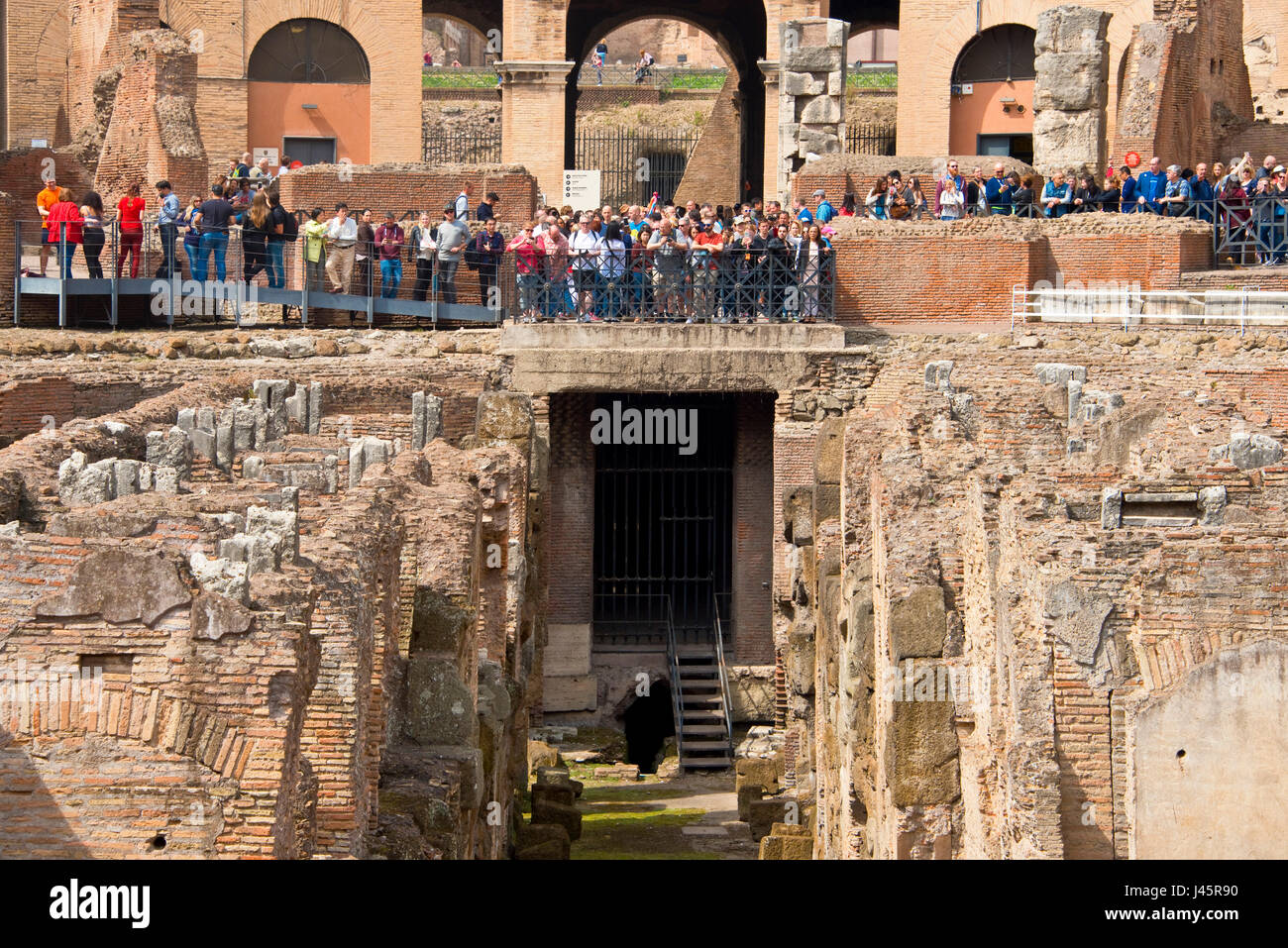 An interior view of the amphitheatre inside the Colosseum with tourists visitors on a sunny day taken from ground level. Stock Photo