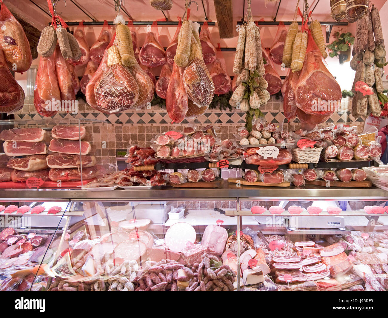 Interior view of a butcher, charcuterie, delicatessen, shop selling traditional Italian cold cuts of meat and whole hams on display. Stock Photo