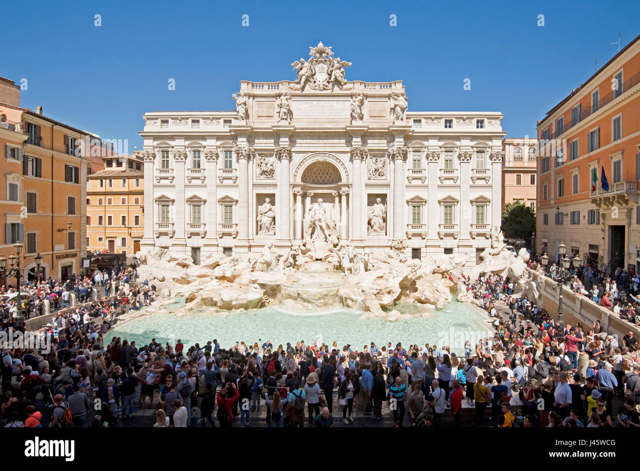 An aerial view of The Trevi Fountain 'Fontana di Trevi' in Rome with crowds of tourists and visitors on a sunny day with blue sky. Stock Photo