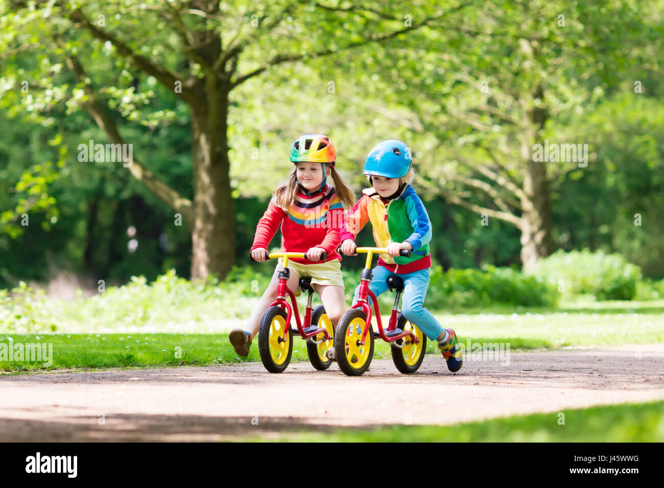 Children riding balance bike. Kids on bicycle in sunny park. Little