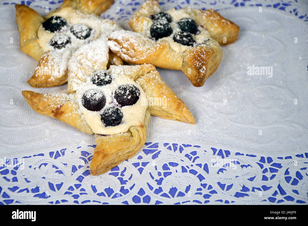 puff pastry pinwheels with blueberries and powdered sugar on paper lace doily Stock Photo