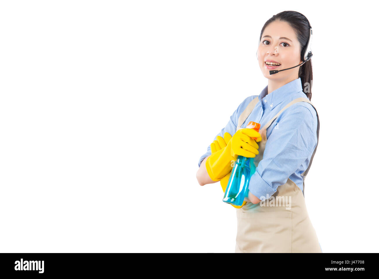 beautiful woman using headset microphone for professional house cleaning online services holding detergent spray bottle. isolated on white background. Stock Photo