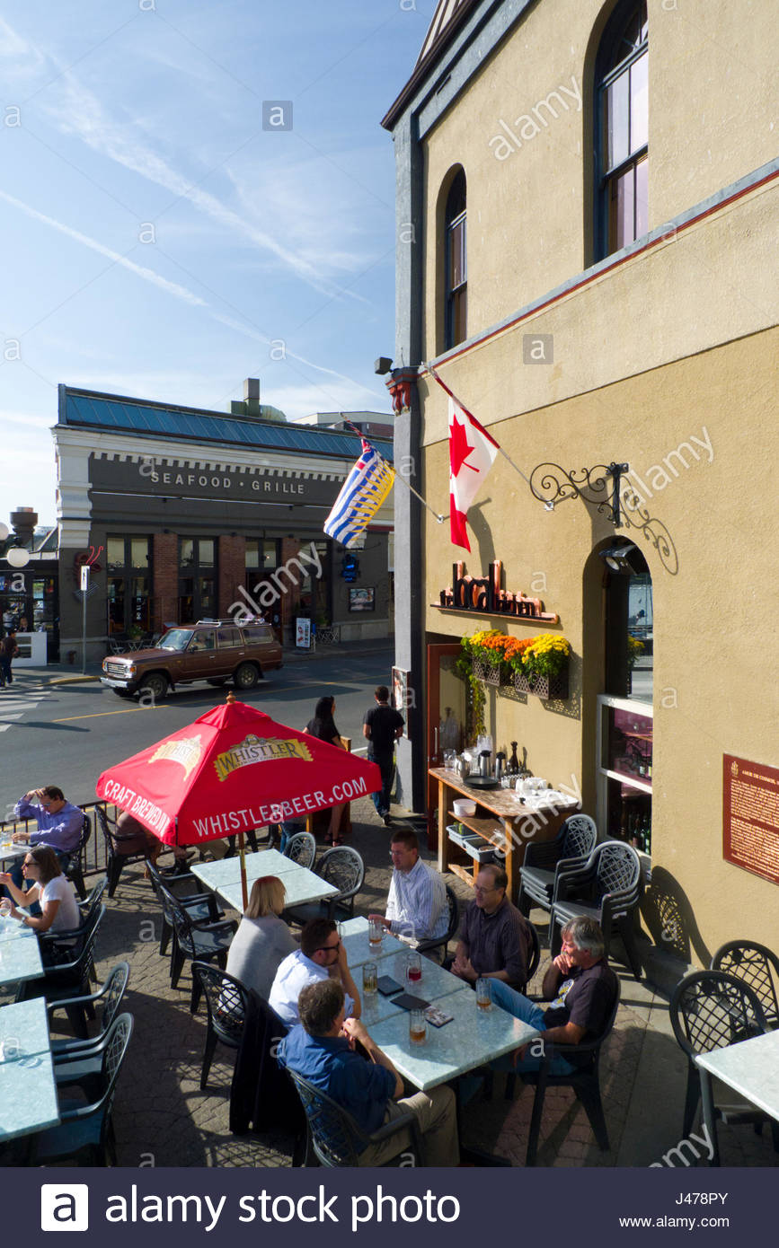 People Sitting At Tables Outside Enjoying The Sunny Weather At The