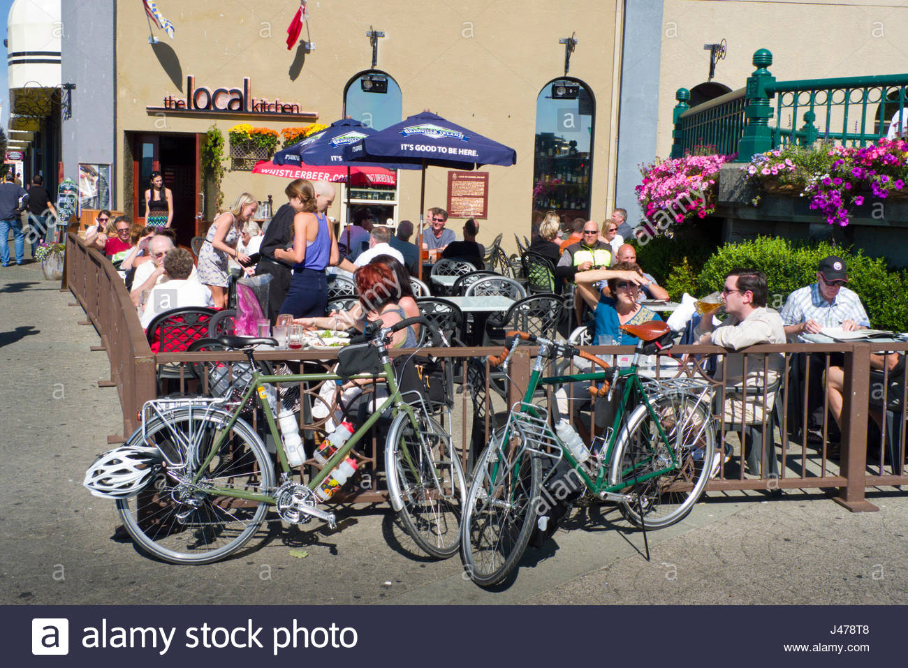 People Sitting At Tables Outside Enjoying The Sunny Weather At The