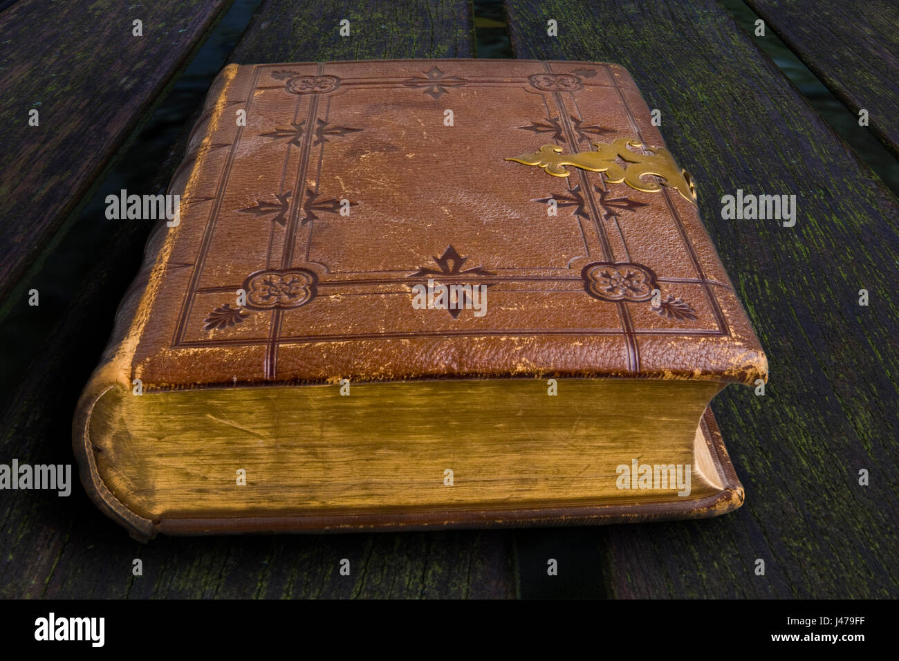 Antique tooled brown leather bound book with metal clasp on a wooden background Stock Photo