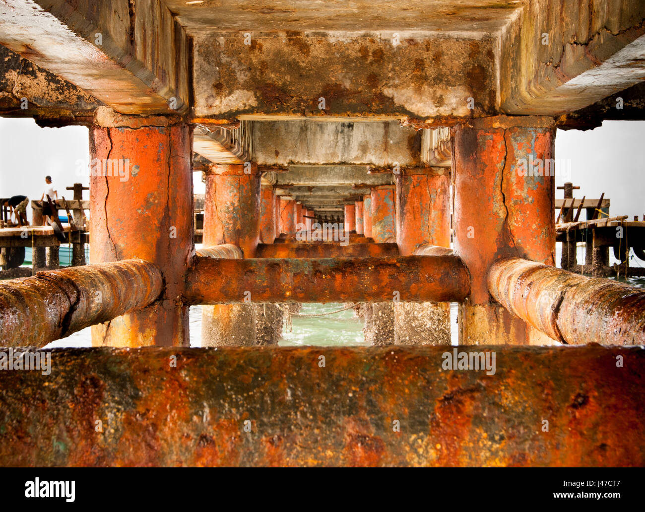 rust covered steel and concrete structure under a wharf creating an interesting depth perspective and background Stock Photo