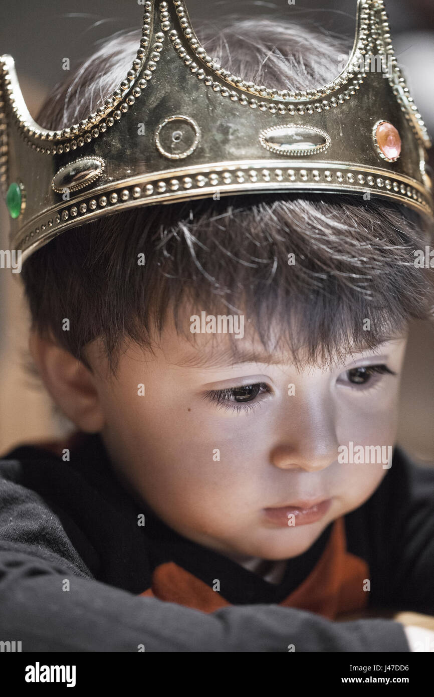 sad little mixed race Asian Caucasian boy with chubby cheeks wearing gold crown pretending to be Shakespeare's hamlet Stock Photo