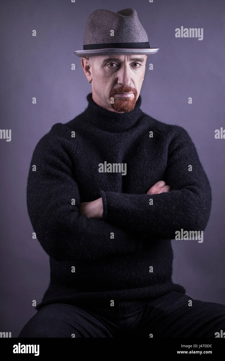 Portrait of a Jewish criminal boxer thug with a red goatee in a black wool turtleneck sweater and grey fedora hat and a gold earring Stock Photo