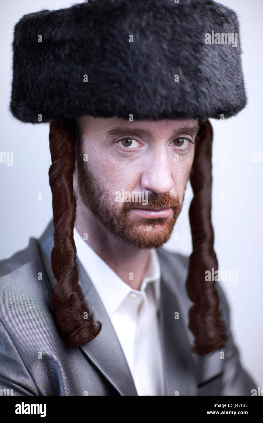 Handsome Orthodox Jewish man Hasidim rabbi with red beard in a large fur hat and side locks in a silver sharkskin suit Stock Photo